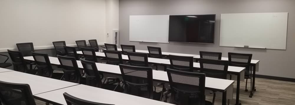 Our conference room, showcasing seating and tables for 35 people, two white boards and a large TV.